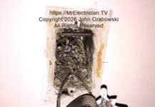 A photo of an old single pole light switch hanging from the electrical switch box by some older wires